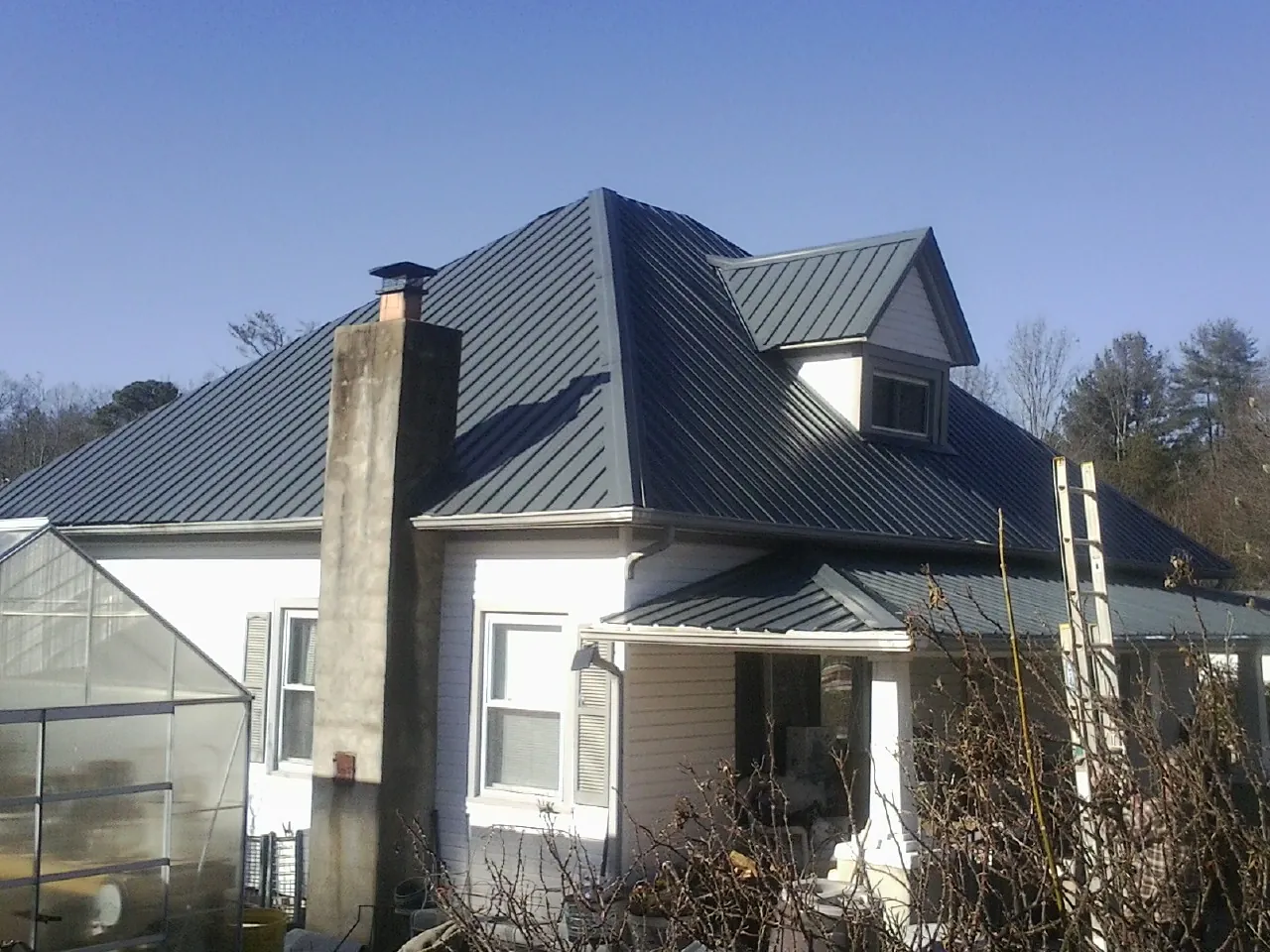 Dark blue standing seam metal roof on a white farmhouse with dormer — Slate & Tile Roof Repair by Roofing Brothers in Gibson Island