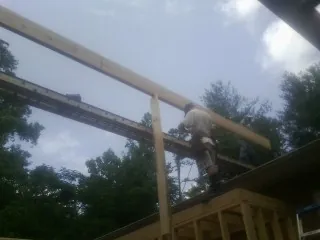 Carpenter setting a ridge beam over a new addition frame — Ice Dam Removal by Roofing Brothers in Gibson Island