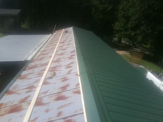 Old rusted panels beside newly installed green metal roofing — Wind Damage Roof Repair by Roofing Brothers in Gibson Island