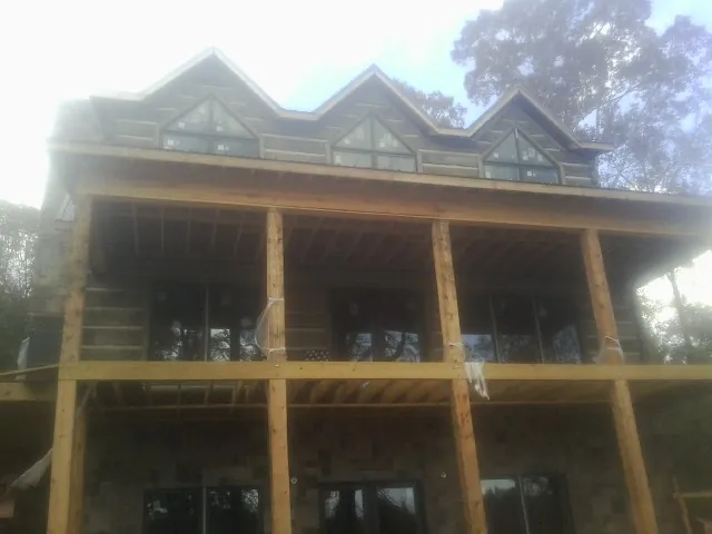 Dormers and porch framing on a large log home under construction — Roof Coating work by our crew in Gibson Island