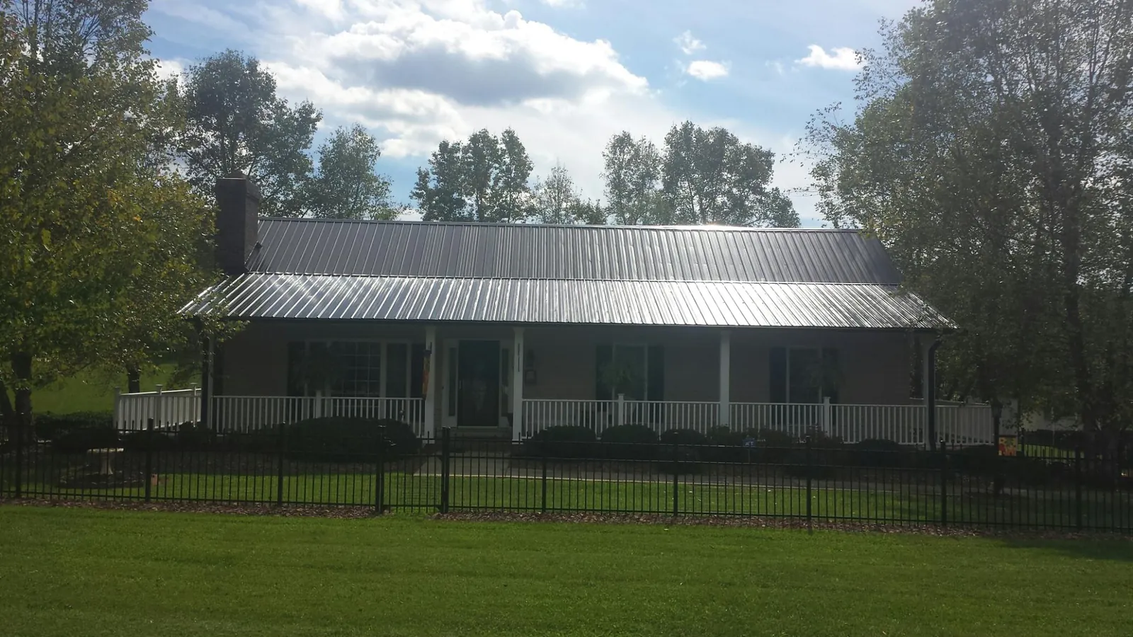 Gray metal roof on a brick ranch with a full width front porch — Gutter Guard Installation work by our crew in Gibson Island
