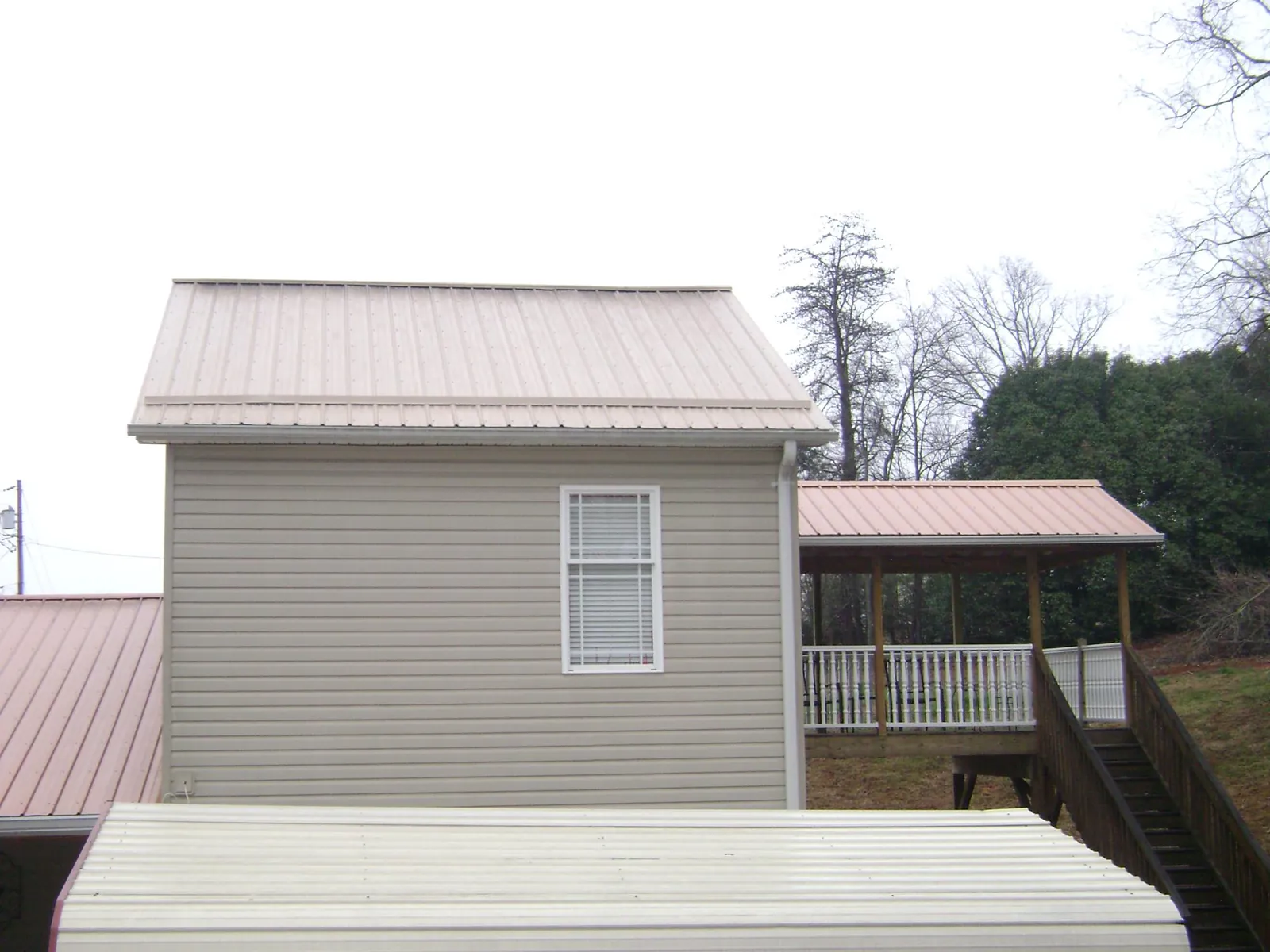 Tan metal roofs on a two story addition and attached porch, from a Roof Replacement job in Gibson Island