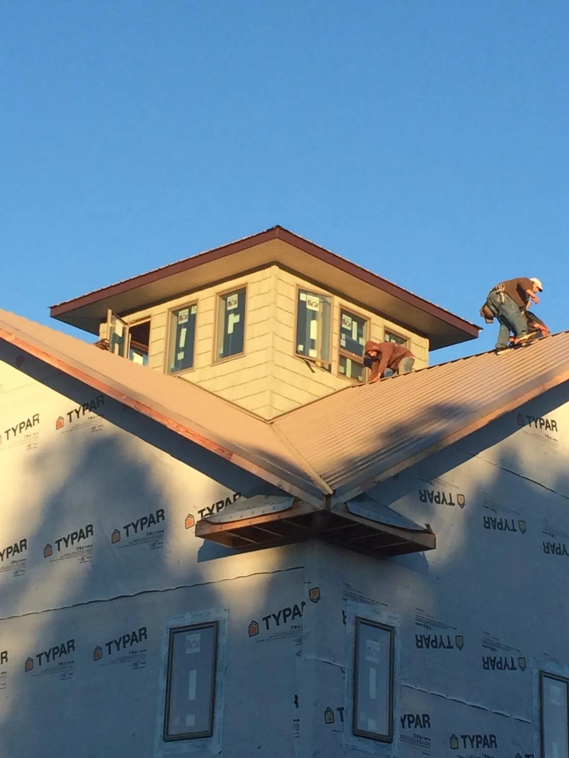 Roofers working around a rooftop cupola on a new metal roof at sunset — Roof Waterproofing in Gibson Island by Roofing Brothers